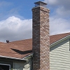 Custom Masonry Brick Chimney with brick corbels just below chimney cap and spark arrestor