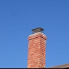Custom Masonry Brick Chimney with brick corbels just below chimney cap and spark arrestor